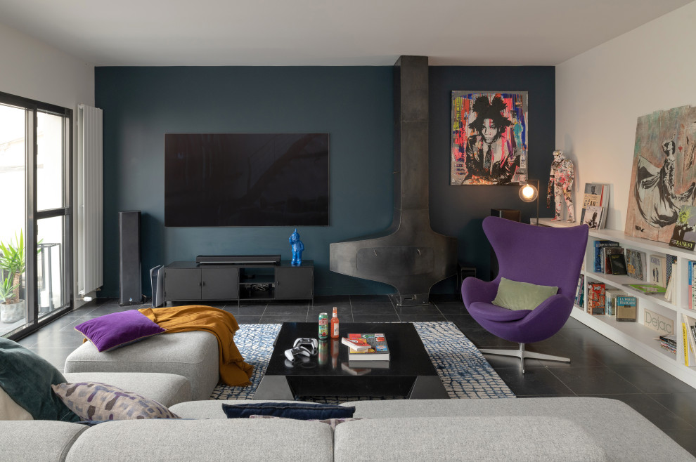 Идея дизайна: огромная открытая, серо-белая гостиная комната в стиле фьюжн с с книжными шкафами и полками, синими стенами, полом из керамической плитки, подвесным камином, фасадом камина из металла, телевизором на стене и синим полом