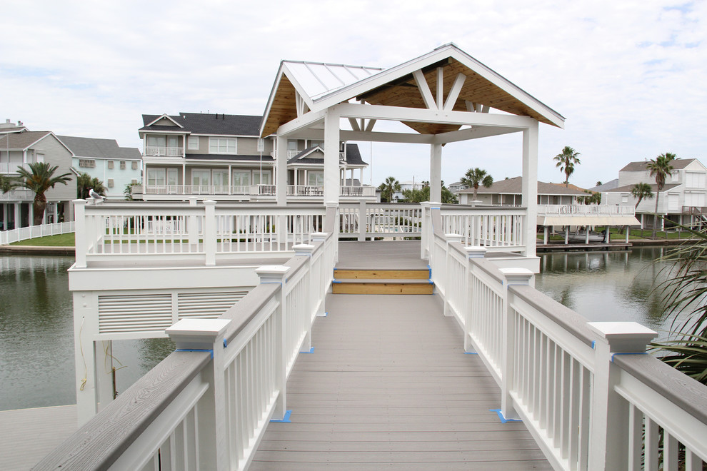 Photo of a large beach style backyard deck in Houston with with dock.