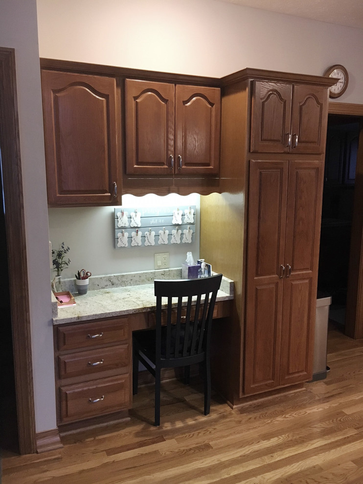Example of a large transitional u-shaped medium tone wood floor eat-in kitchen design with an undermount sink, raised-panel cabinets, medium tone wood cabinets, granite countertops, white backsplash, ceramic backsplash, stainless steel appliances and an island