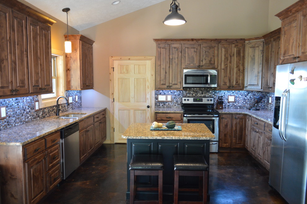Kitchen - mid-sized rustic concrete floor and brown floor kitchen idea with an undermount sink, brown cabinets, granite countertops, multicolored backsplash, stainless steel appliances, an island and raised-panel cabinets