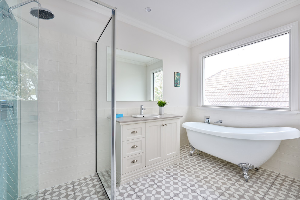 This is an example of a beach style 3/4 bathroom in Melbourne with shaker cabinets, beige cabinets, a claw-foot tub, a corner shower, a drop-in sink, grey floor, a hinged shower door and grey benchtops.