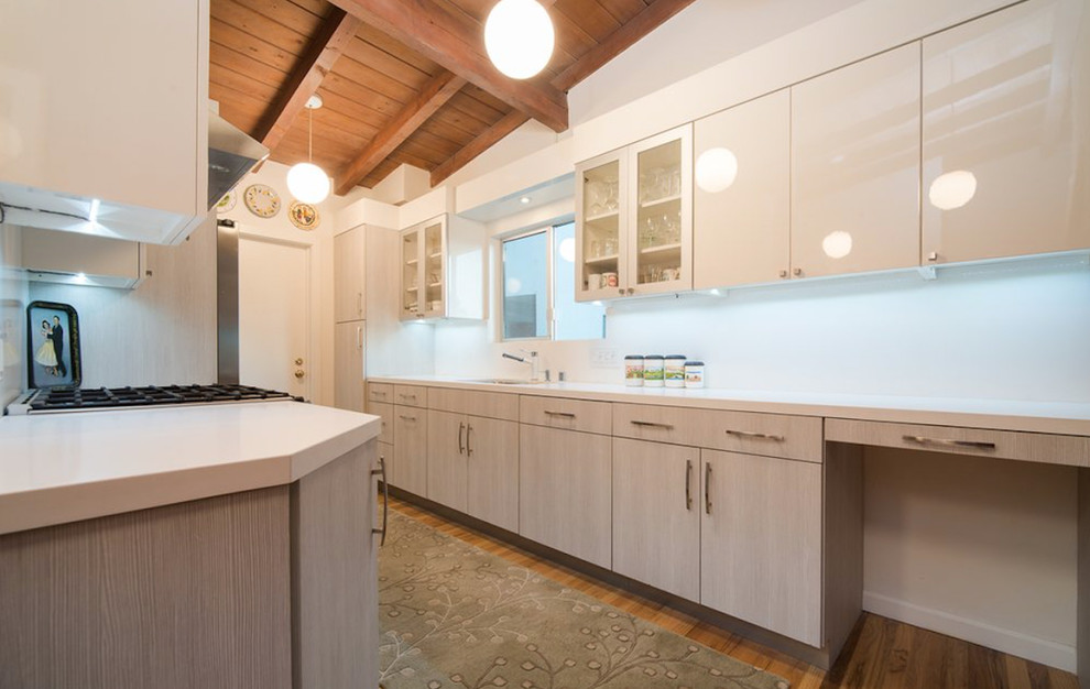 Photo of a mid-sized modern galley separate kitchen in Los Angeles with an undermount sink, flat-panel cabinets, beige cabinets, quartz benchtops, white splashback, stone slab splashback, stainless steel appliances, light hardwood floors, no island and brown floor.