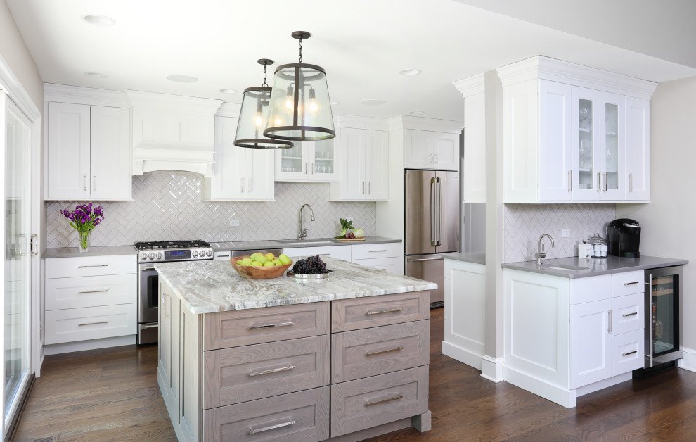 This is an example of a large transitional u-shaped eat-in kitchen in Chicago with an undermount sink, white cabinets, grey splashback, ceramic splashback, with island, brown floor, grey benchtop, recessed-panel cabinets, quartzite benchtops, stainless steel appliances and medium hardwood floors.