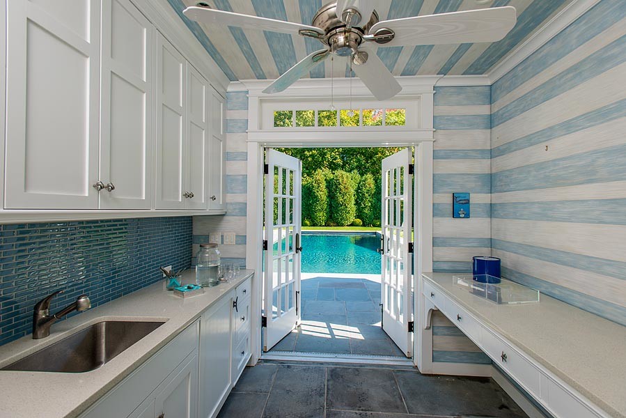 This is an example of a mid-sized beach style galley separate kitchen in New York with an undermount sink, beaded inset cabinets, white cabinets, quartz benchtops, blue splashback, ceramic splashback, slate floors and grey floor.