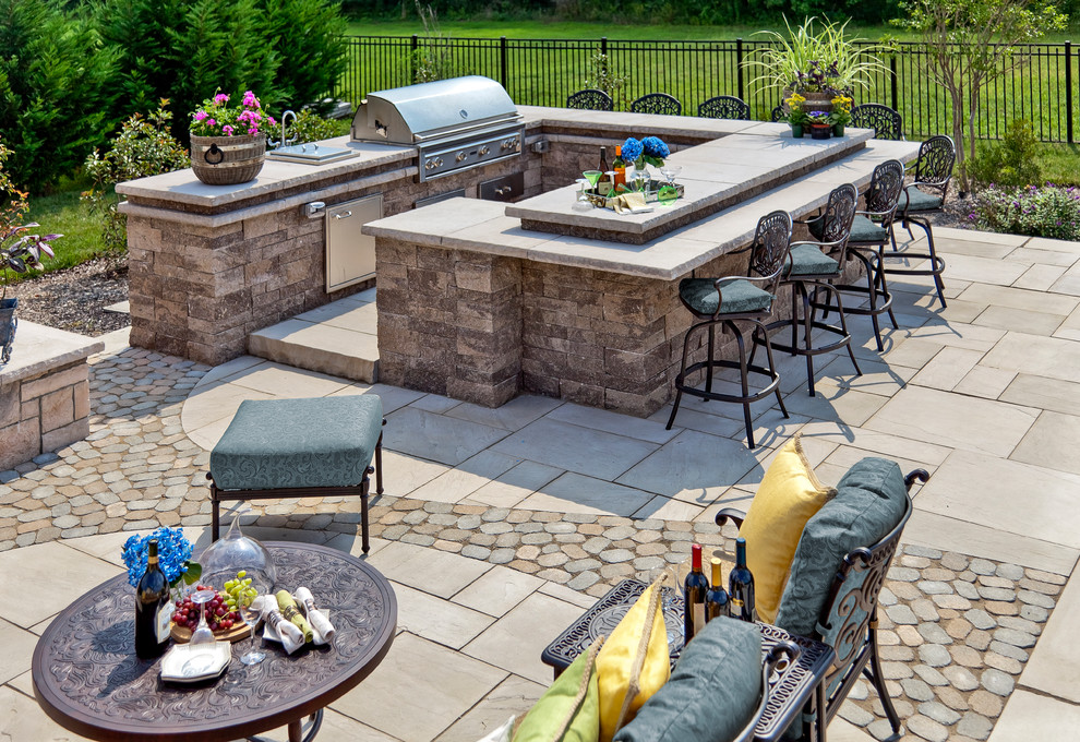 Expansive traditional backyard patio in Philadelphia with an outdoor kitchen, natural stone pavers and no cover.