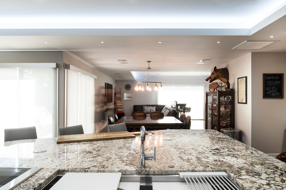 Eat-in kitchen - large transitional ceramic tile and beige floor eat-in kitchen idea with an undermount sink, shaker cabinets, brown cabinets, granite countertops, white backsplash, glass tile backsplash, stainless steel appliances and an island