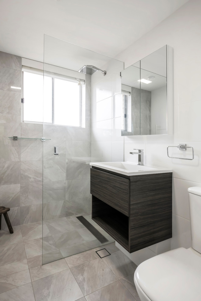 Свежая идея для дизайна: маленькая главная ванная комната в современном стиле с плоскими фасадами, темными деревянными фасадами, открытым душем, унитазом-моноблоком, белой плиткой, керамической плиткой, белыми стенами, полом из керамогранита, монолитной раковиной, столешницей из искусственного камня, серым полом, открытым душем, белой столешницей, тумбой под одну раковину и подвесной тумбой для на участке и в саду - отличное фото интерьера
