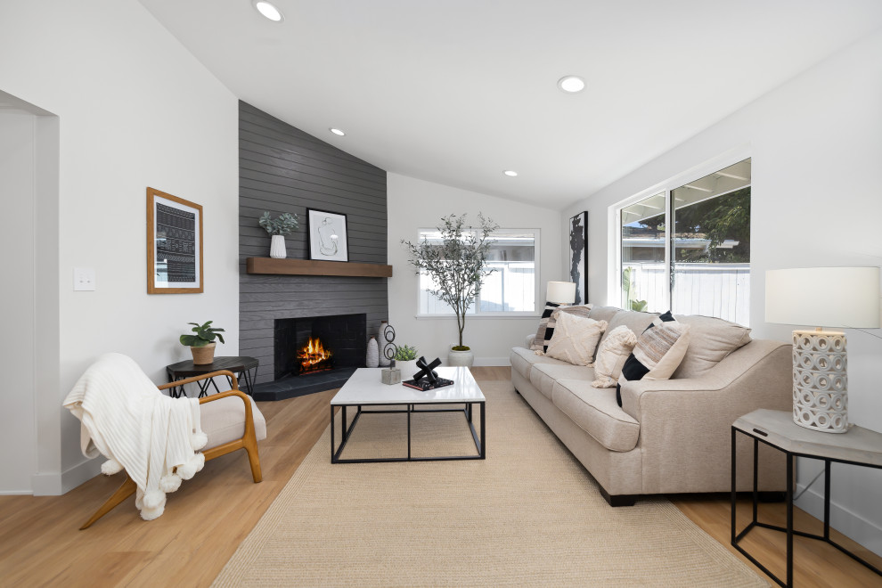 Design ideas for a mid-sized midcentury open concept living room in Orange County with white walls, laminate floors, a corner fireplace and vaulted.