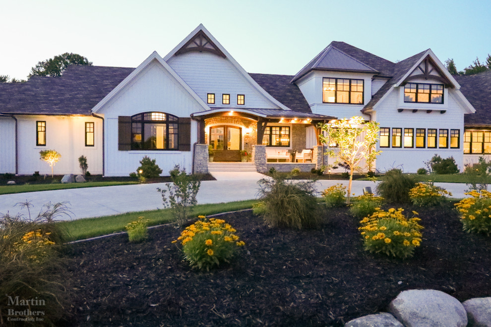 Modern Farmhouse - Front elevation featuring cedar gable brackets, Celect Board & Batten and D7 Shake siding in white; Boral trim boards; cedar lined ceilings; cedar brackets; copper gutters and downspouts; metal roofs and GAF Slateline English Gray Slate roofing shingles. Buechel Stone Fond du Lac Cambrian Blend stone on porch front and posts.   Landscaping by Linton's Enchanted Gardens.

General contracting by Martin Bros. Contracting, Inc.; Architecture by Helman Sechrist Architecture; Home Design by Maple & White Design; Photography by Marie Kinney Photography.

Images are the property of Martin Bros. Contracting, Inc. and may not be used without written permission.