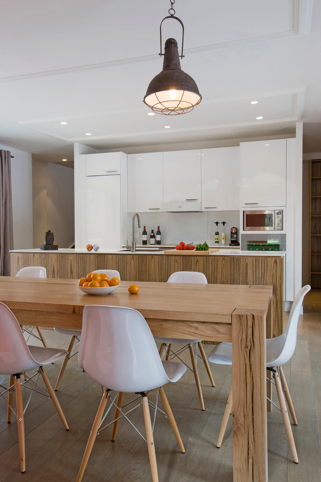 Photo of a large contemporary galley eat-in kitchen in Paris with flat-panel cabinets, white cabinets, white splashback, panelled appliances, medium hardwood floors and with island.