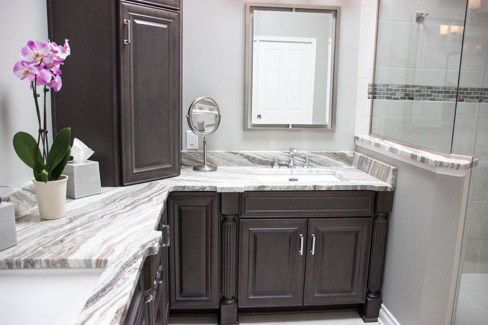 This is an example of a mid-sized transitional master bathroom in Cleveland with grey cabinets, a freestanding tub, a curbless shower, a one-piece toilet, white tile, porcelain tile, grey walls, porcelain floors, an undermount sink, granite benchtops and raised-panel cabinets.