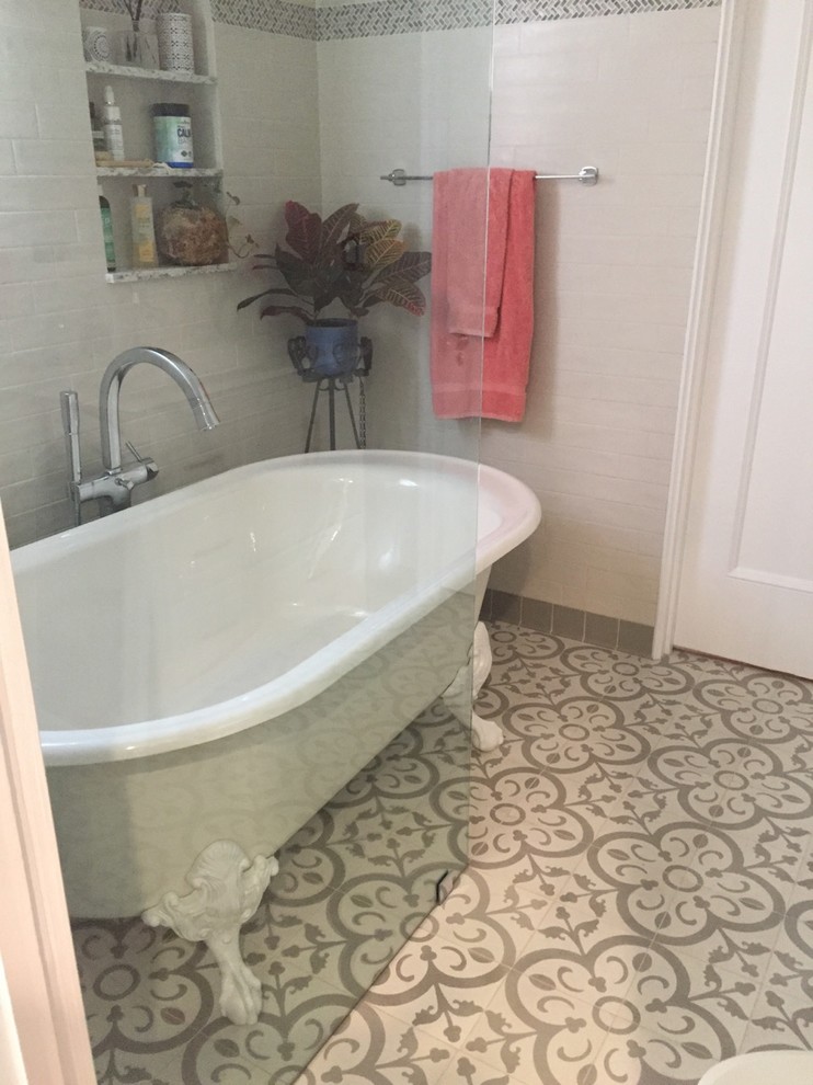 Inspiration for a mid-sized mediterranean 3/4 bathroom in Los Angeles with furniture-like cabinets, white cabinets, a claw-foot tub, a shower/bathtub combo, a one-piece toilet, gray tile, subway tile, grey walls, cement tiles, an integrated sink, tile benchtops, grey floor and an open shower.