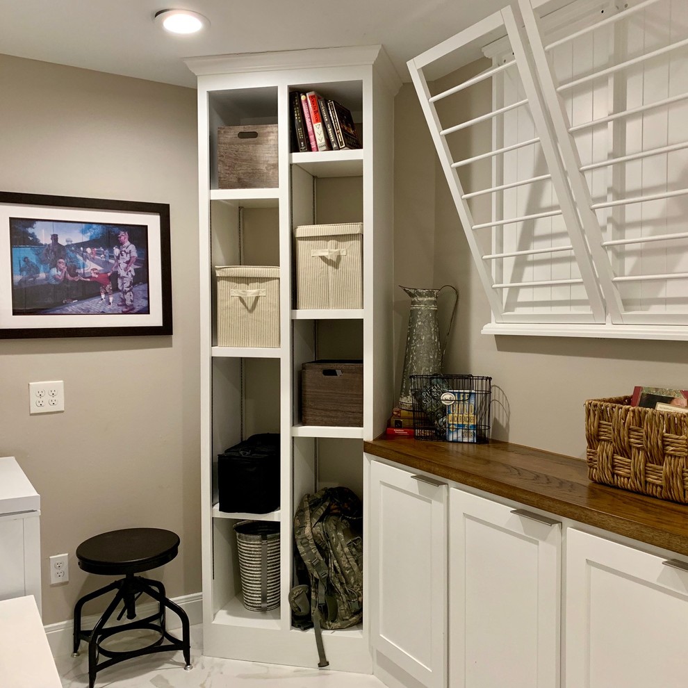 Inspiration for a small transitional u-shaped utility room in Houston with shaker cabinets, white cabinets, wood benchtops, grey walls, a side-by-side washer and dryer, white floor, brown benchtop and marble floors.