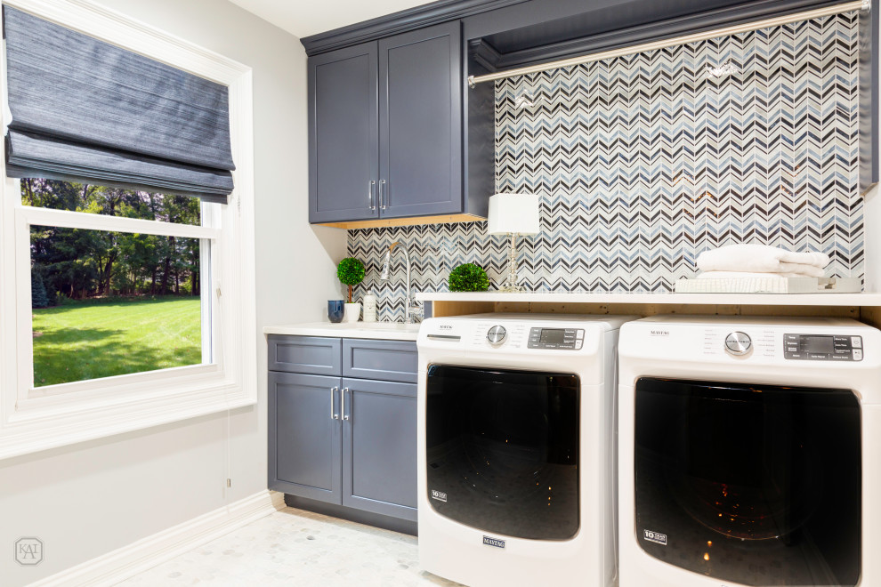 Small transitional laundry room in Chicago with an undermount sink, recessed-panel cabinets, blue cabinets, quartz benchtops, multi-coloured splashback, grey walls, marble floors, a side-by-side washer and dryer, multi-coloured floor, white benchtop and mosaic tile splashback.