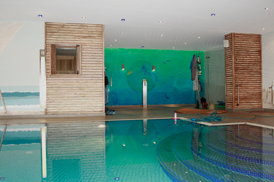 Idée de décoration pour une grande piscine intérieure marine rectangle avec des pavés en pierre naturelle.