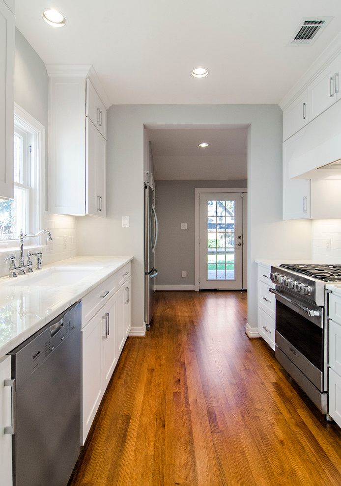 Inspiration for a transitional galley eat-in kitchen remodel in Dallas with an undermount sink, shaker cabinets, white cabinets, marble countertops, white backsplash, subway tile backsplash and stainless steel appliances