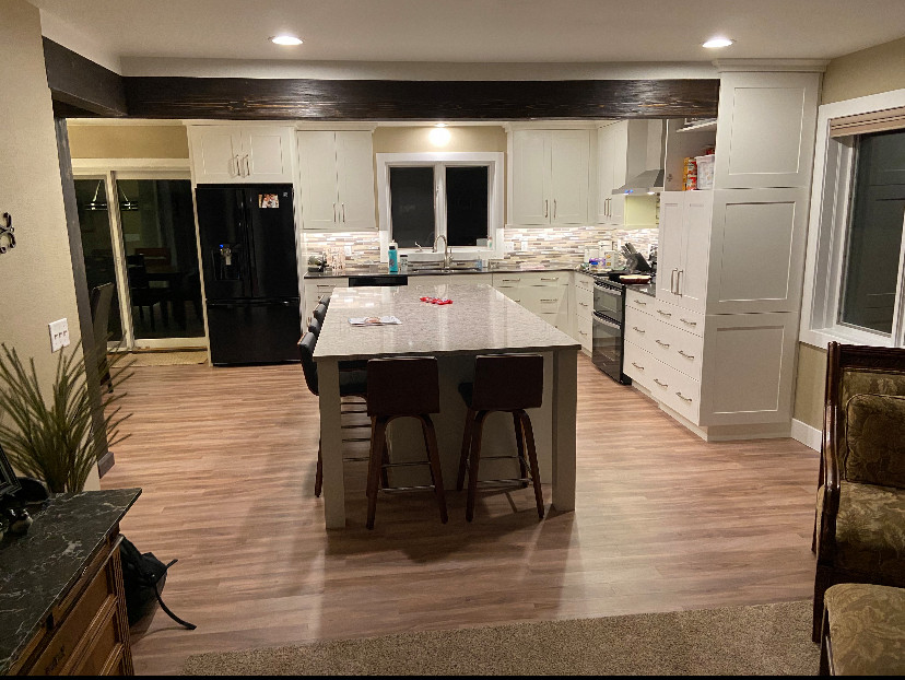 Mid-sized transitional single-wall vinyl floor and multicolored floor eat-in kitchen photo with an undermount sink, shaker cabinets, white cabinets, quartz countertops, multicolored backsplash, metal backsplash, black appliances, an island and white countertops