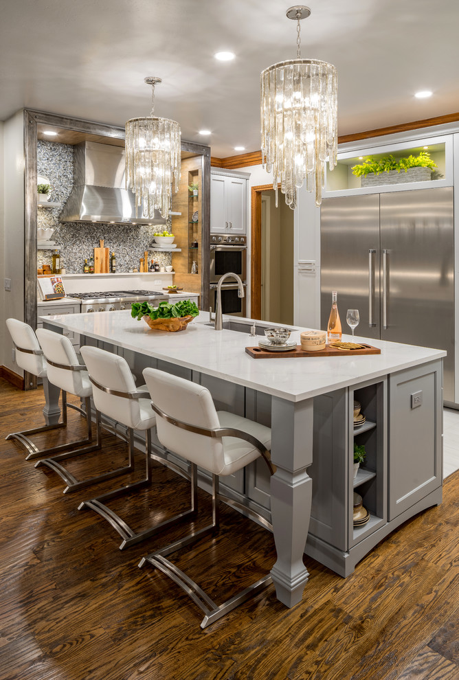 This is an example of a large transitional open plan kitchen in Oklahoma City with a single-bowl sink, shaker cabinets, grey cabinets, quartz benchtops, grey splashback, porcelain splashback, stainless steel appliances, medium hardwood floors, with island and brown floor.