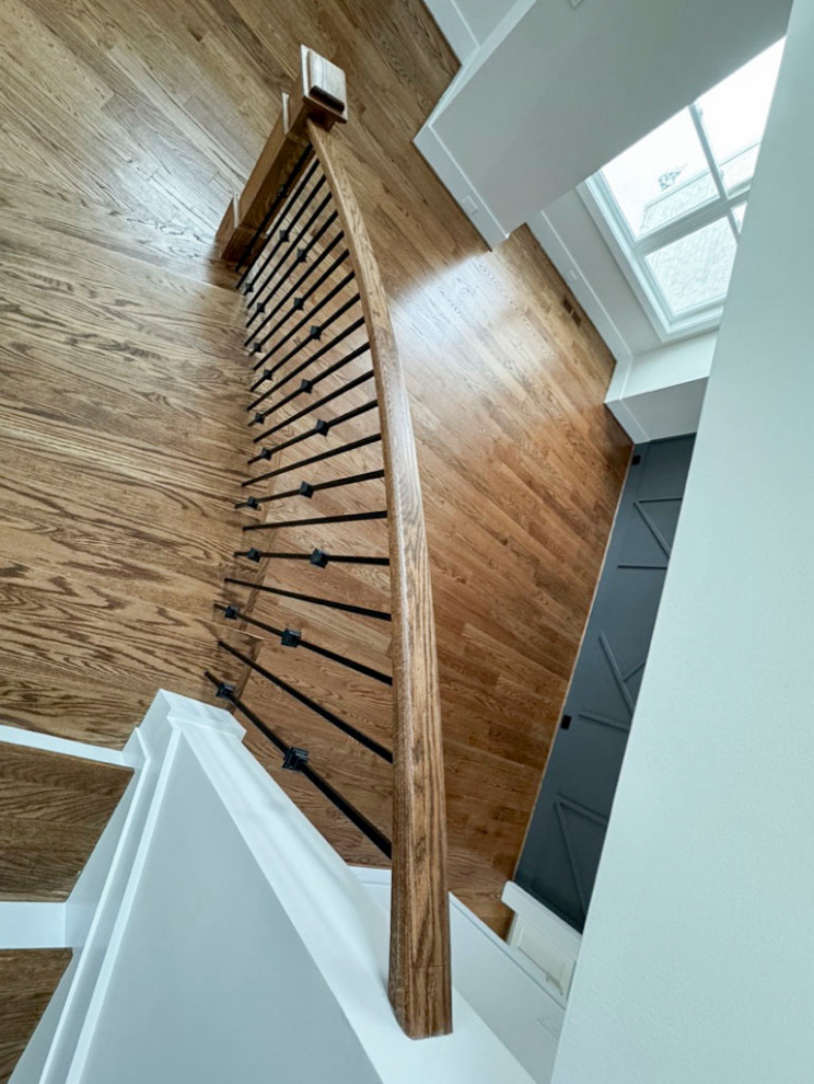 This is an example of a mid-sized transitional wood curved staircase in DC Metro with wood risers and mixed railing.