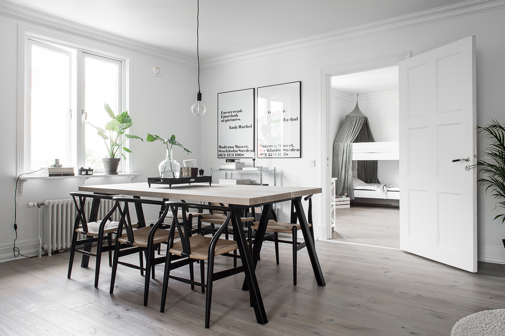 This is an example of a mid-sized scandinavian separate dining room in Gothenburg with white walls, light hardwood floors and no fireplace.