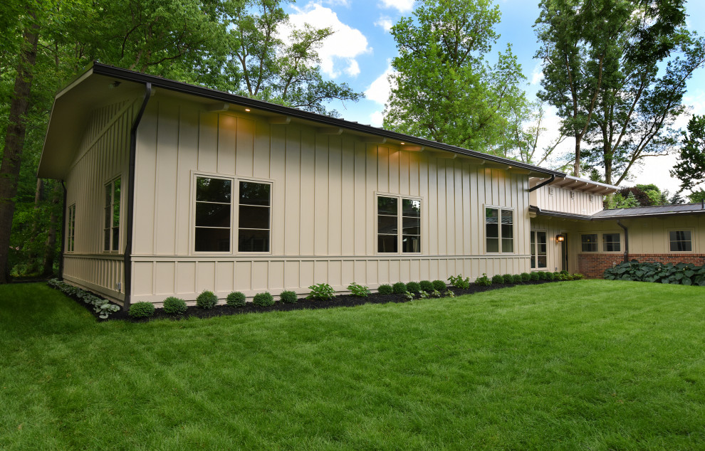 Modelo de fachada de casa beige y negra industrial de tamaño medio de dos plantas con revestimientos combinados, tejado a dos aguas, tejado de metal y panel y listón