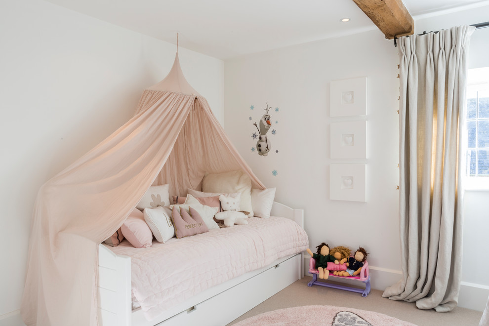 This is an example of a mid-sized country kids' bedroom for kids 4-10 years old and girls in Gloucestershire with white walls, carpet and beige floor.