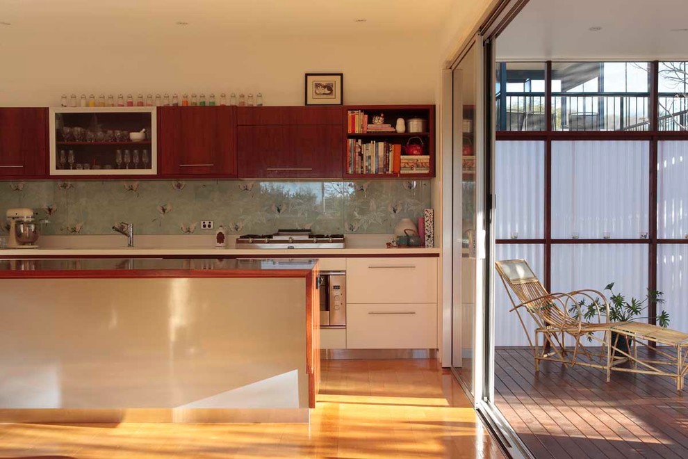 This is an example of a mid-sized traditional galley eat-in kitchen in Brisbane with an undermount sink, white cabinets, wood benchtops, glass sheet splashback, stainless steel appliances, light hardwood floors and with island.