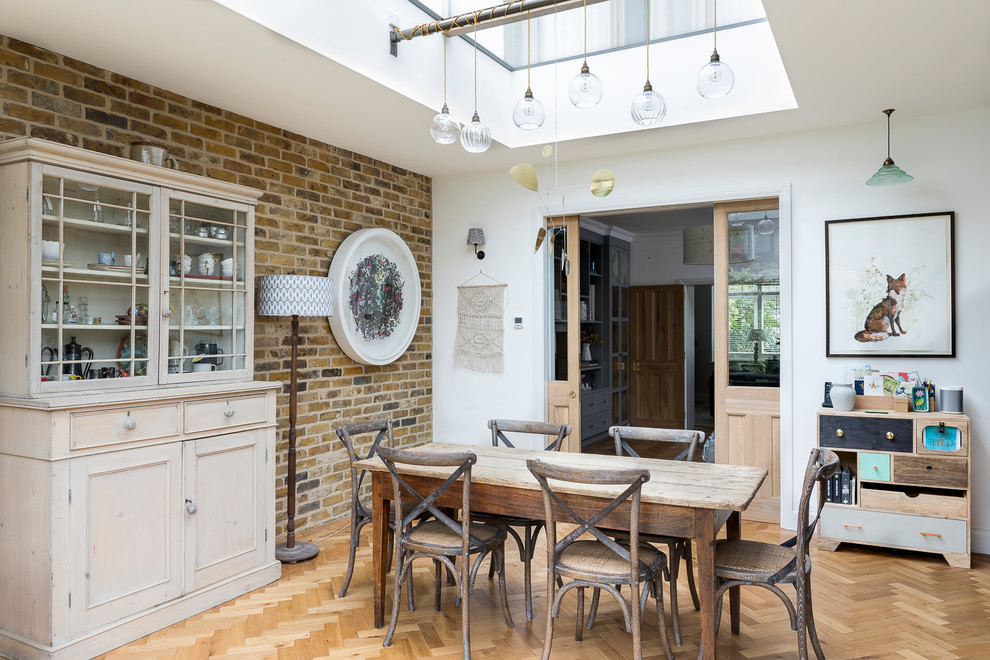 Inspiration for a mid-sized eclectic dining room in London with white walls, light hardwood floors and brown floor.