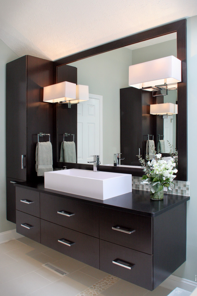 Photo of a mid-sized modern master bathroom in Cleveland with flat-panel cabinets, brown cabinets, a freestanding tub, an open shower, a one-piece toilet, green tile, glass sheet wall, green walls, porcelain floors, a vessel sink, soapstone benchtops, grey floor and a hinged shower door.