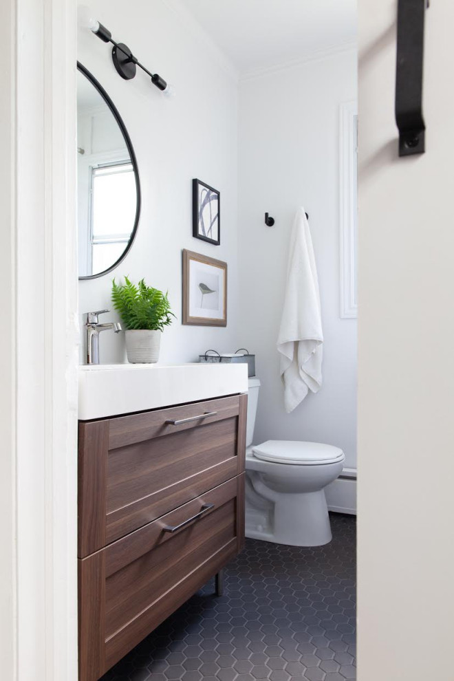 Photo of a small modern bathroom in Toronto with shaker cabinets, dark wood cabinets, white walls, porcelain floors, an integrated sink, engineered quartz benchtops, black floor and white benchtops.