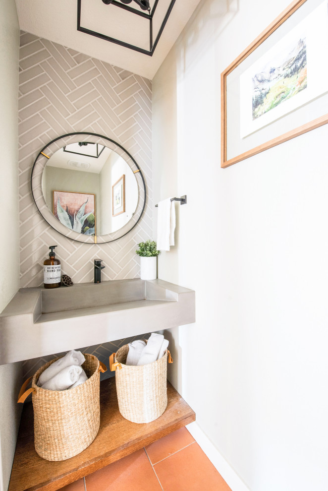 Inspiration for a small modern powder room in Denver with grey cabinets, gray tile, subway tile, beige walls, terra-cotta floors, a wall-mount sink, concrete benchtops, orange floor, grey benchtops and a floating vanity.