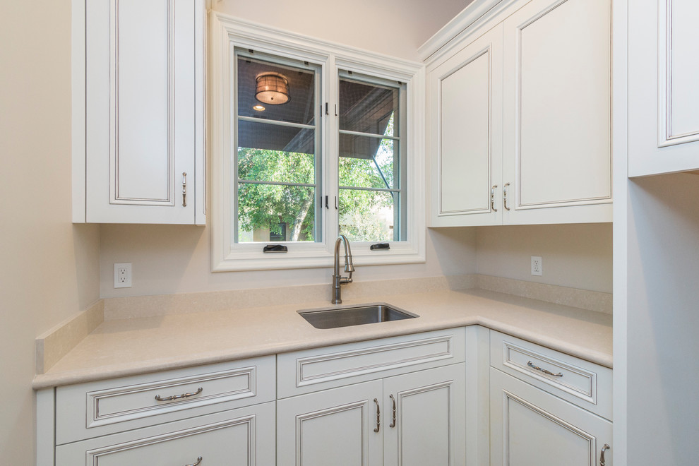 Design ideas for an expansive transitional u-shaped dedicated laundry room in Phoenix with an undermount sink, raised-panel cabinets, beige cabinets, solid surface benchtops, grey walls, terra-cotta floors, a side-by-side washer and dryer and red floor.