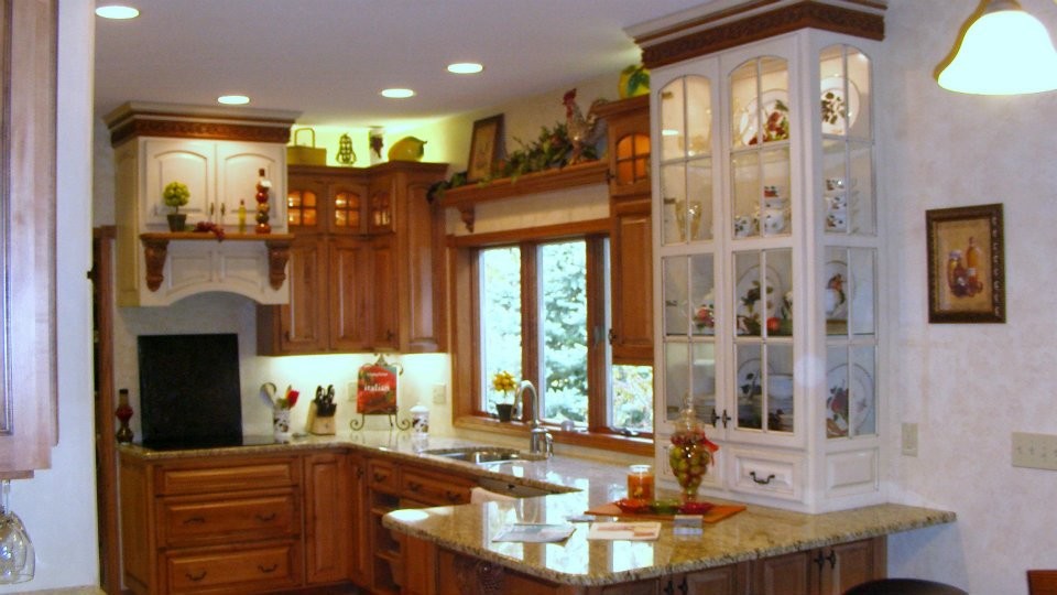 This is an example of a country u-shaped kitchen in Other with an undermount sink, raised-panel cabinets, granite benchtops, stainless steel appliances, medium hardwood floors and a peninsula.