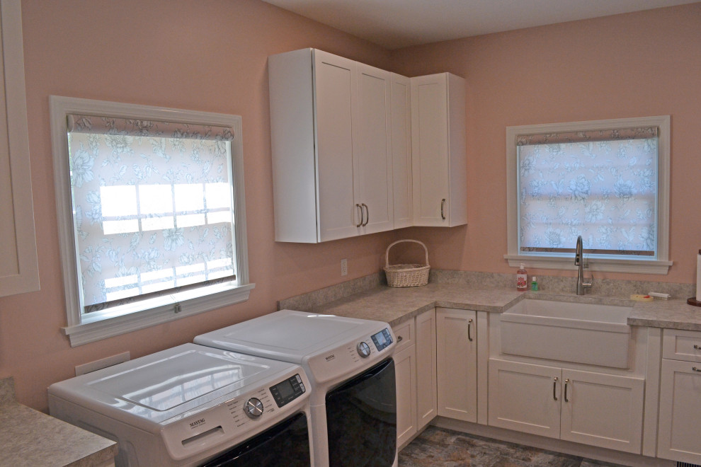 Große Klassische Waschküche in L-Form mit Landhausspüle, Schrankfronten im Shaker-Stil, weißen Schränken, Laminat-Arbeitsplatte, rosa Wandfarbe, Keramikboden, Waschmaschine und Trockner nebeneinander, buntem Boden und rosa Arbeitsplatte in Sonstige
