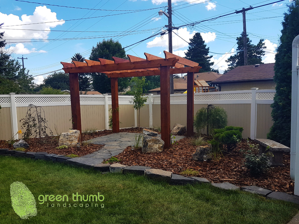 Photo of a rustic full sun backyard stone retaining wall landscape in Edmonton for summer.