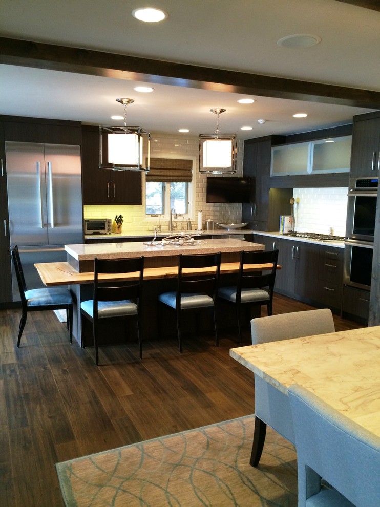 Mid-sized transitional l-shaped dark wood floor and brown floor open concept kitchen photo in Denver with an undermount sink, flat-panel cabinets, dark wood cabinets, granite countertops, white backsplash, subway tile backsplash, stainless steel appliances and an island
