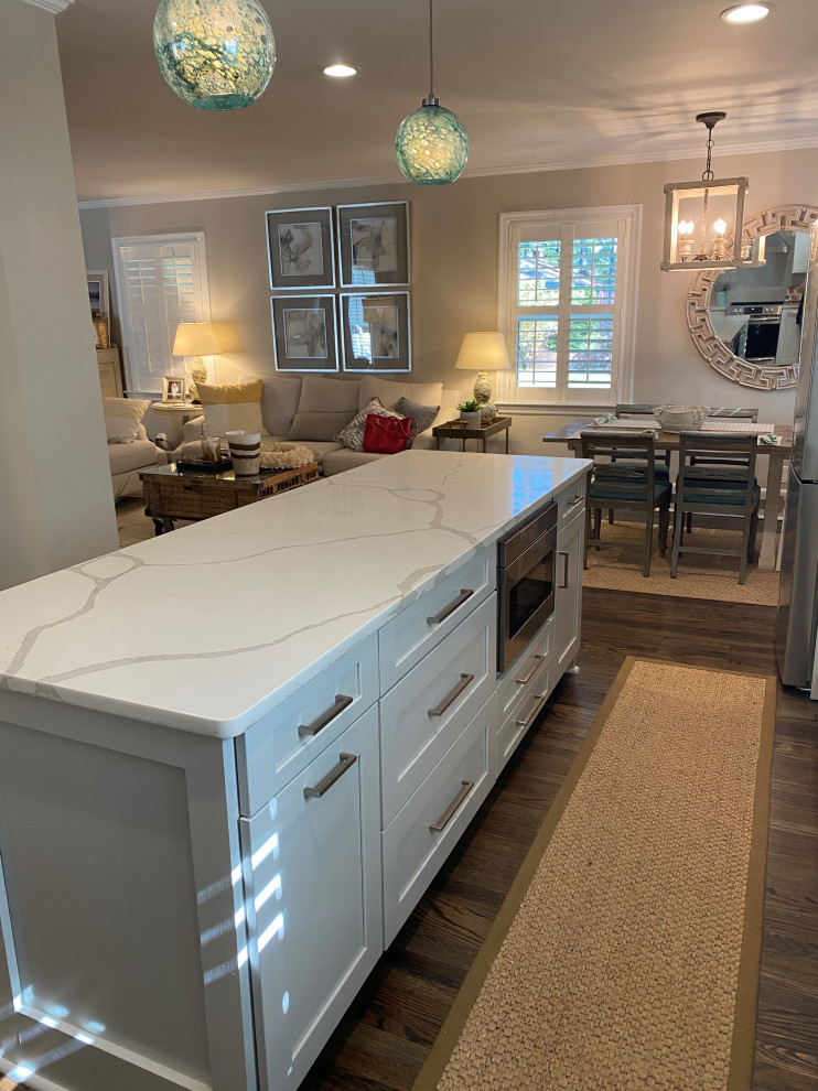 Design ideas for a mid-sized transitional l-shaped eat-in kitchen in Other with a farmhouse sink, shaker cabinets, white cabinets, quartz benchtops, grey splashback, ceramic splashback, stainless steel appliances, dark hardwood floors, with island, brown floor and white benchtop.
