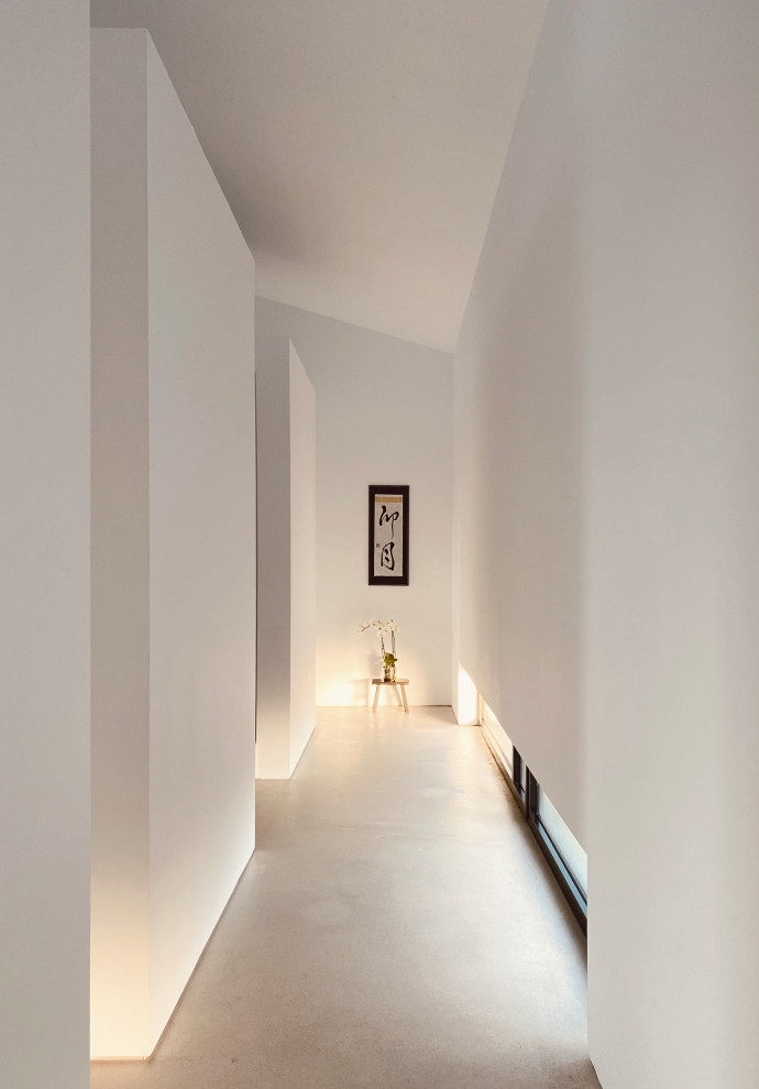 マドリードにあるお手頃価格の広いインダストリアルスタイルのおしゃれな廊下 (白い壁、グレーの床) の写真