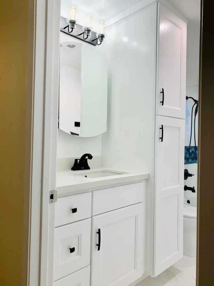 Photo of a mid-sized contemporary kids bathroom in Los Angeles with shaker cabinets, white cabinets, a drop-in tub, a shower/bathtub combo, a two-piece toilet, white tile, ceramic tile, white walls, porcelain floors, an undermount sink, quartzite benchtops, white floor, a hinged shower door, beige benchtops, a single vanity and a built-in vanity.