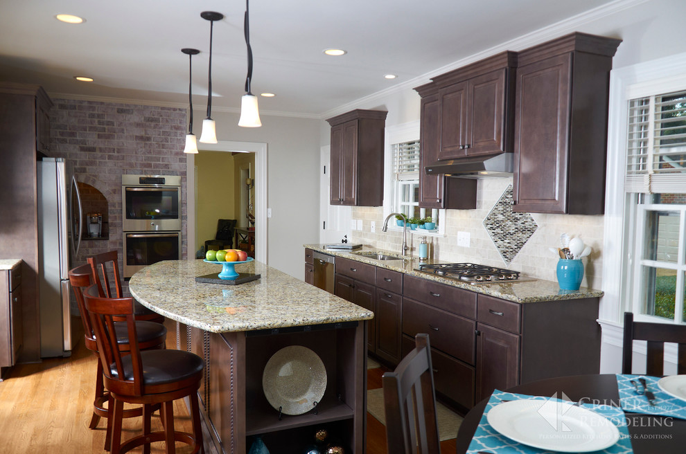 Eat-in kitchen - transitional light wood floor eat-in kitchen idea with shaker cabinets, dark wood cabinets, granite countertops, beige backsplash, glass tile backsplash, stainless steel appliances and an island