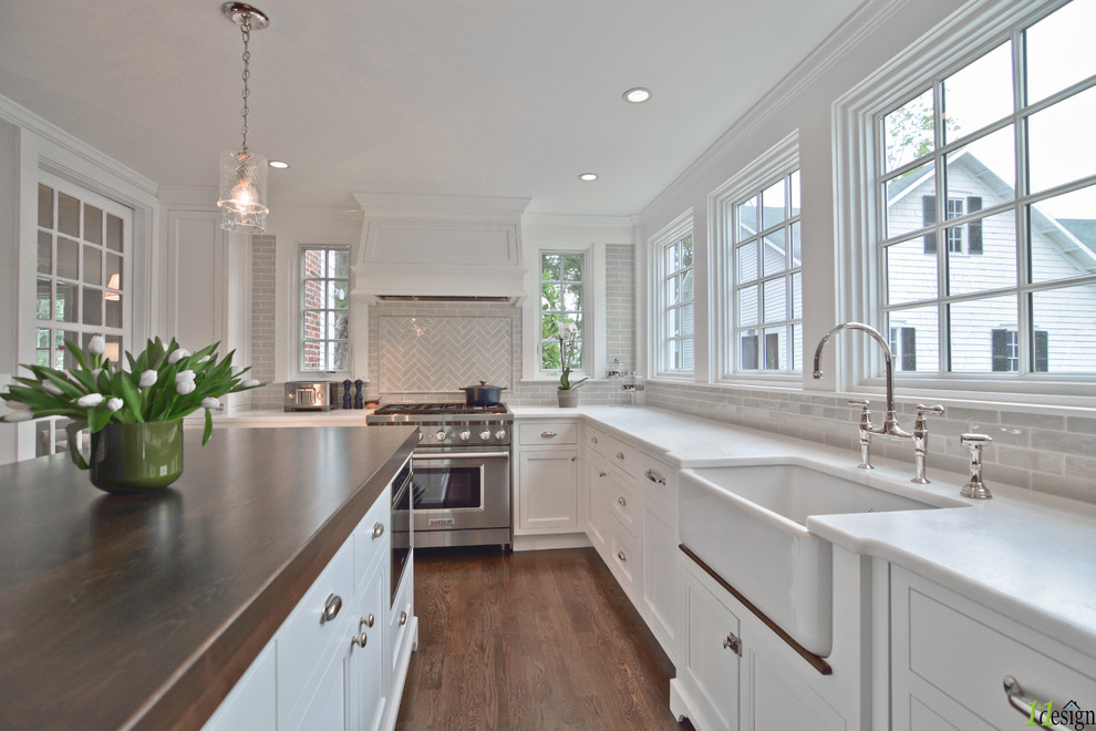 Large traditional u-shaped separate kitchen in Boston with a farmhouse sink, recessed-panel cabinets, white cabinets, quartzite benchtops, beige splashback, subway tile splashback, panelled appliances, dark hardwood floors, with island and brown floor.