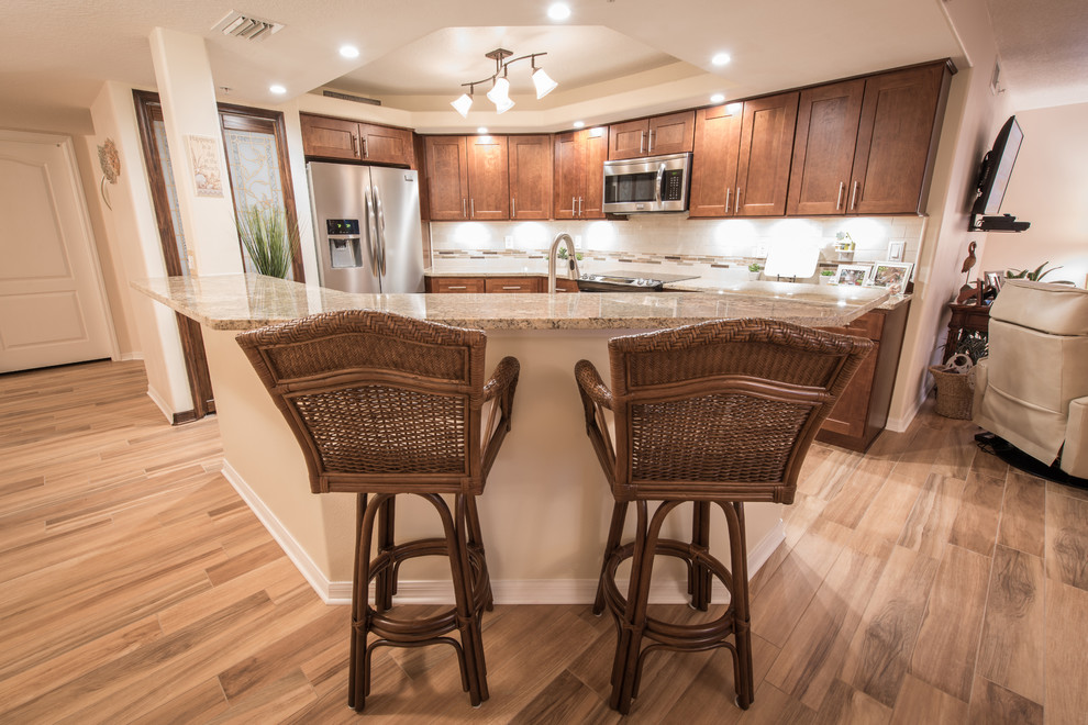 Inspiration for a mid-sized transitional u-shaped porcelain tile eat-in kitchen remodel with an undermount sink, shaker cabinets, dark wood cabinets, granite countertops, beige backsplash, stone tile backsplash, stainless steel appliances and an island