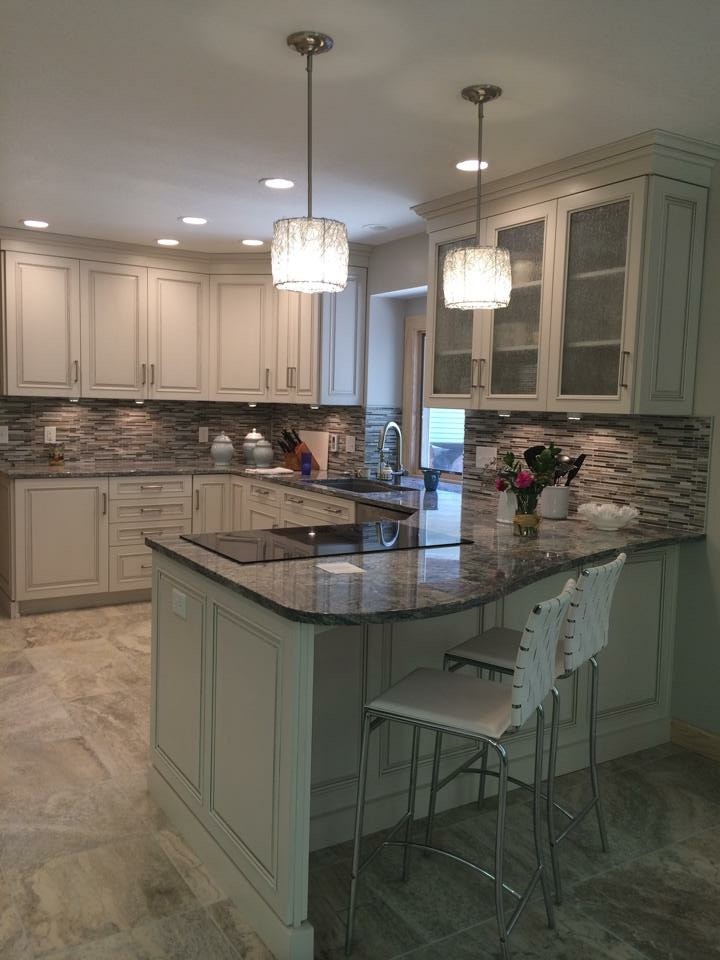Example of a large transitional u-shaped travertine floor eat-in kitchen design with an undermount sink, raised-panel cabinets, beige cabinets, granite countertops, multicolored backsplash, matchstick tile backsplash and a peninsula