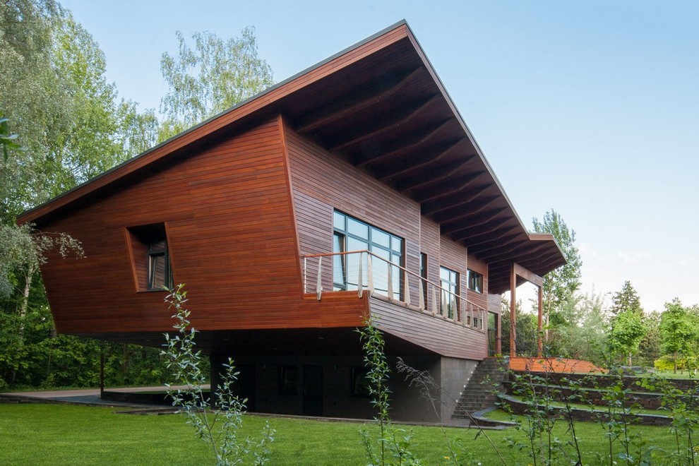 Photo of a large contemporary two-storey brown exterior in Moscow with wood siding and a shed roof.
