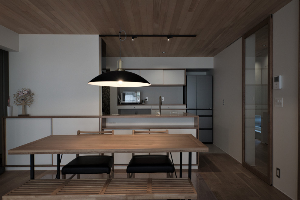 Photo of a small grey and cream single-wall kitchen/diner in Other with a submerged sink, beaded cabinets, white cabinets, stainless steel worktops, white splashback, glass sheet splashback, coloured appliances, medium hardwood flooring, an island, orange floors, orange worktops and a wood ceiling.