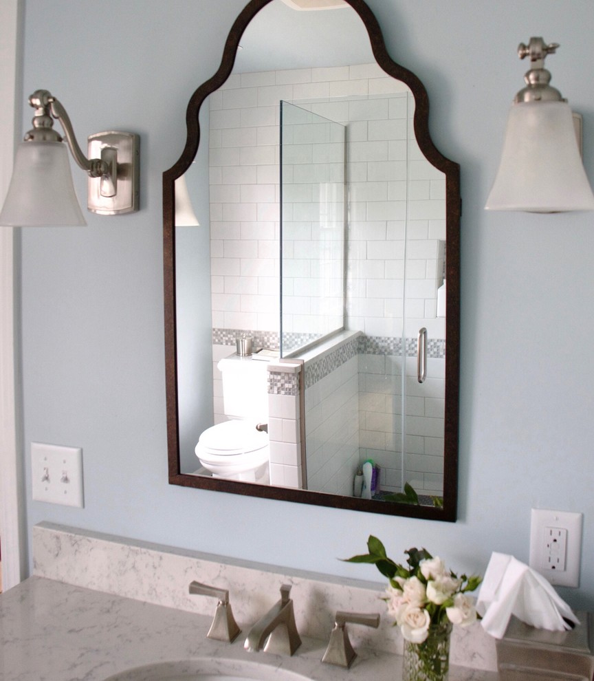 Corner shower - small transitional master white tile and ceramic tile ceramic tile corner shower idea with shaker cabinets, dark wood cabinets, a two-piece toilet, blue walls, an undermount sink and quartz countertops