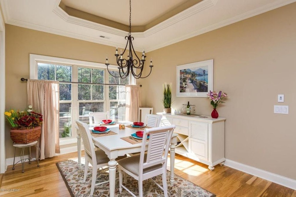 Mid-sized beach style separate dining room in Wilmington with beige walls, light hardwood floors, no fireplace and brown floor.