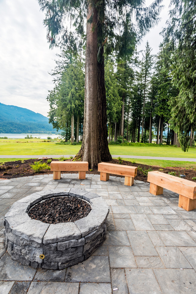 Photo of an expansive country side yard partial sun formal garden in Vancouver with a fire feature and brick pavers.