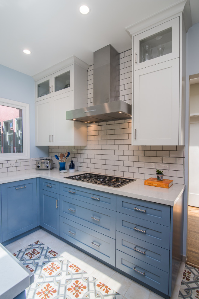 Mid-sized transitional u-shaped ceramic tile and multicolored floor enclosed kitchen photo with an undermount sink, shaker cabinets, blue cabinets, limestone countertops, white backsplash, subway tile backsplash, stainless steel appliances, a peninsula and white countertops