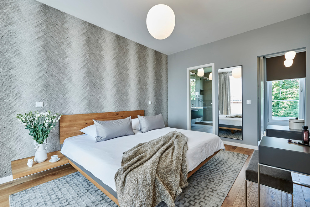 Mid-sized mediterranean bedroom in Hamburg with grey walls, medium hardwood floors and brown floor.